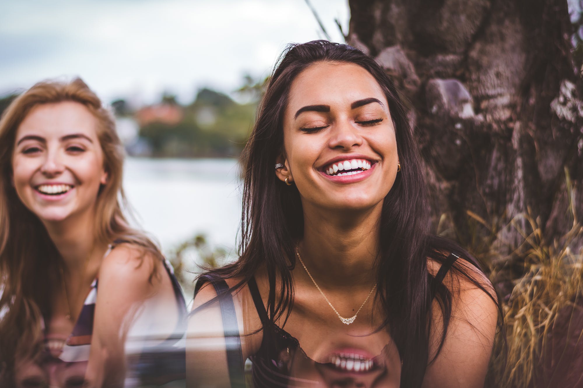 Woman and her friend laughing. They have a clear complexion because they have discovered their best skincare routine.