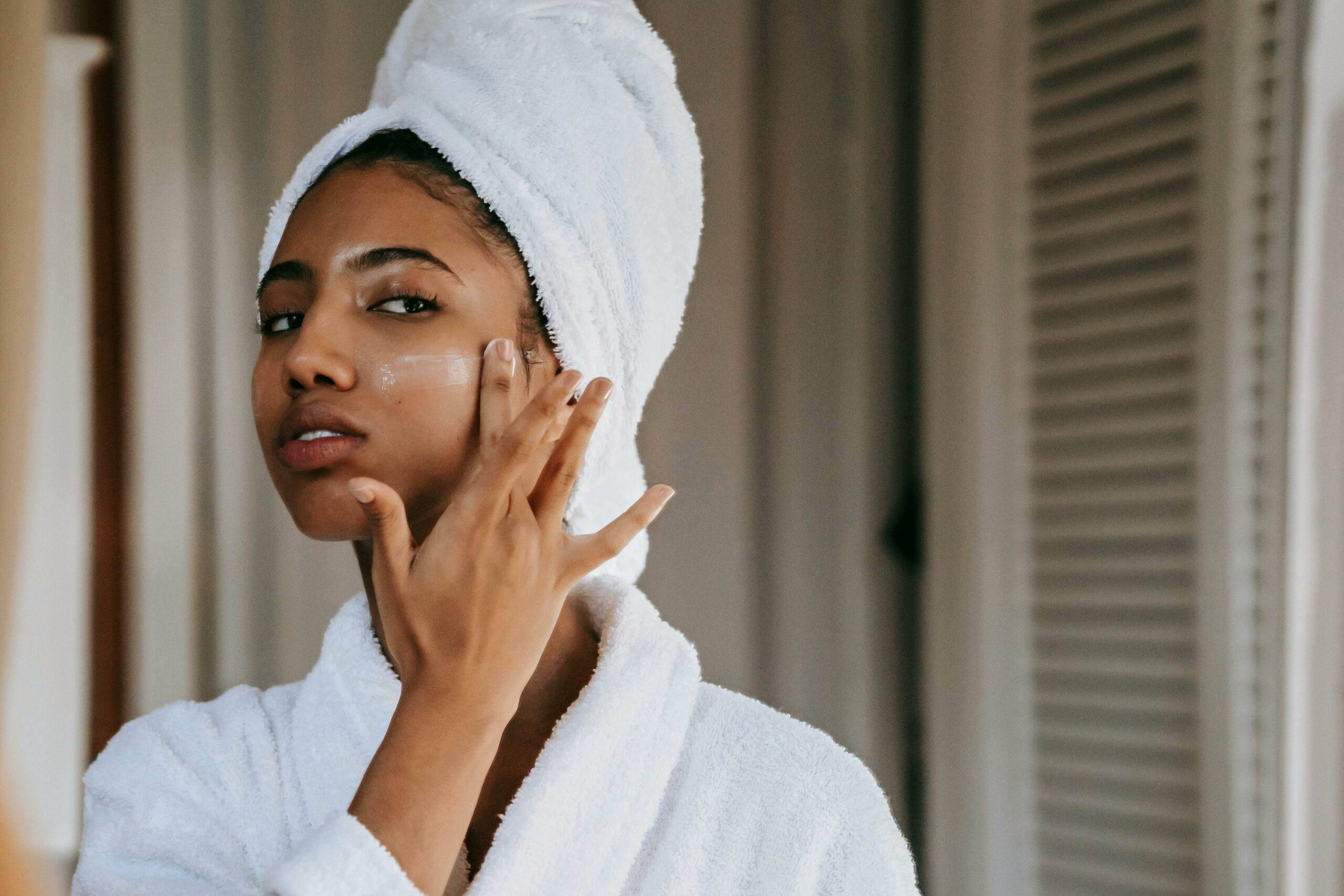 Woman spreading moisturizer on her face to improve skin hydration.