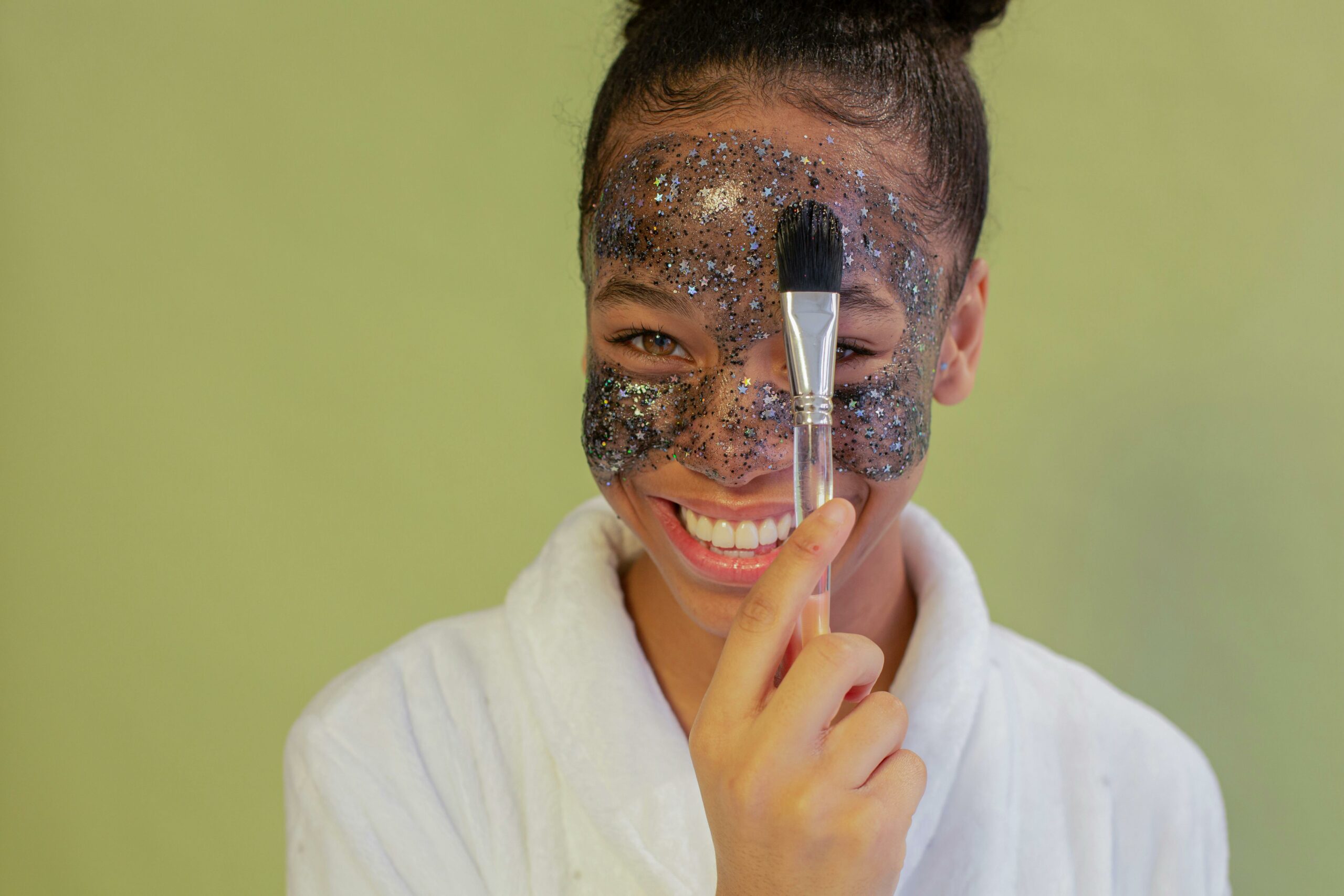 Woman using a glitter mask as a fun exfoliant to represent skincare that exfoliates the face.